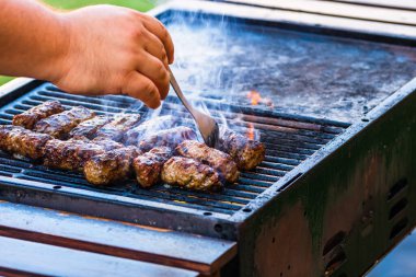 Mangalda mici ya da mititei denilen rulo köfteleri hazırlıyorum. Izgarayı alev ve dumanla yakın..