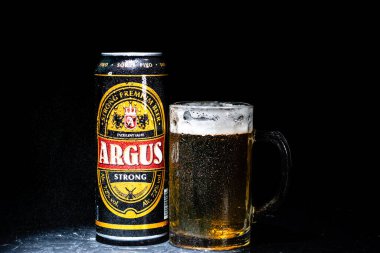 Bir kutu Argus birası ve arka planda bira bardağı. Romanya 'nın Bükreş kentinde 2021 yılında çekilen illüstrasyon fotoğrafı