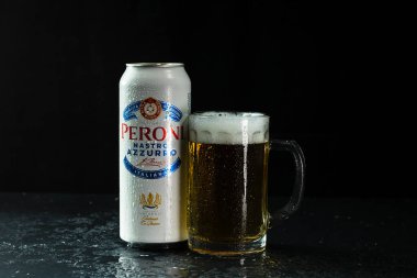 Arka planda bir kutu Peroni Nastro Azzurro birası ve bira bardağı. Romanya 'nın Bükreş kentinde 2021 yılında çekilen illüstrasyon fotoğrafı