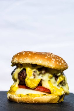 Beyaz arka planda erimiş peynirli taze sığır etli çizburger.