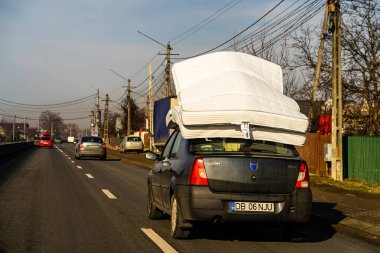 Arabanın çatısındaki yatak, Dacia Logan Romanya 'nın Bükreş kentindeki çatıda yatak taşıyor, 2021