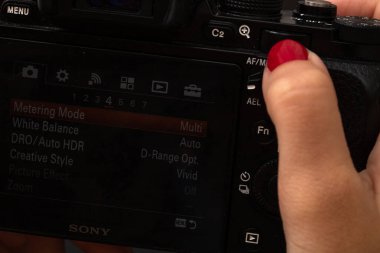 Dijital fotoğraf makinesi kullanan bir el. Bükreş, Romanya, 2021 'de siyah ahşap arka planda aynasız fotoğraf makinesi