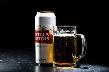 Bir kutu Stella Artois birası ve arka planda bira bardağı. Romanya 'nın Bükreş kentinde 2021 yılında çekilen illüstrasyon fotoğrafı