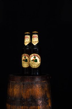 Bir şişe Birra Moretti birası. Ahşap fıçının üzerinde, koyu arkaplanlı. Bükreş, Romanya, 2021