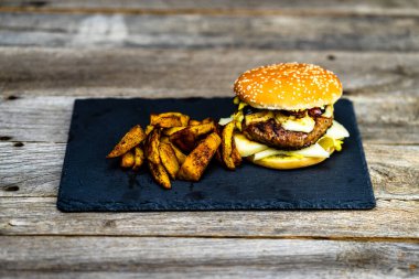 Ev yapımı taze peynirli burger ve ahşap masada kızarmış patates.