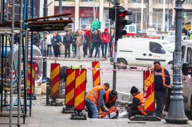 Romanya 'nın Bükreş kentindeki kaldırımları kesen ve onaran yansıtıcı yelek giyen işçilerin arka planı, 2020