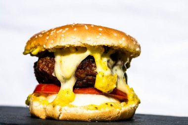 Beyaz arka planda erimiş peynirli taze sığır etli çizburger.