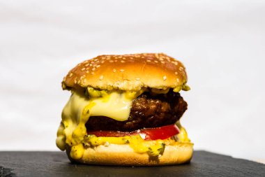 Beyaz arka planda erimiş peynirli taze sığır etli çizburger.