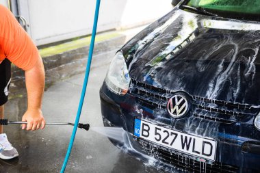 Otomobil yıkama istasyonunda araba yıkama ve temizleme. Romanya 'nın Bükreş kentinde yüksek basınçlı su kullanan araba yıkama, 2021