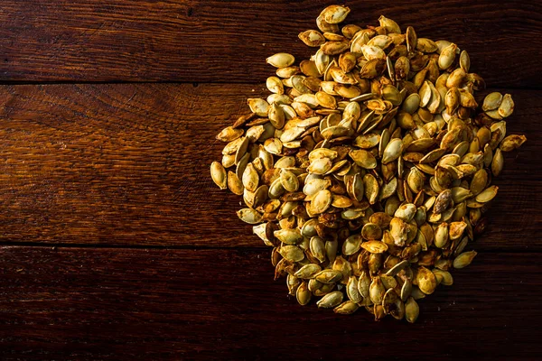 Ahşap masada kavrulmuş tuzlu kabak çekirdeği.