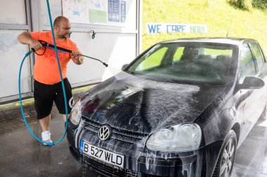 Otomobil yıkama istasyonunda araba yıkama ve temizleme. Romanya 'nın Bükreş kentinde yüksek basınçlı su kullanan araba yıkama, 2021