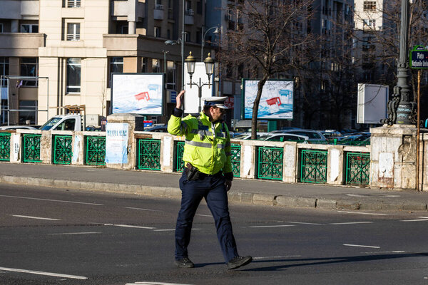 Police agent, Romanian Traffic Police (Politia Rutiera) directing traffic during  rush hour in downtown Bucharest, Romania, 2021