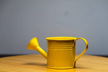 Tahta masadaki sarı sulama kutusu.