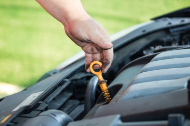 Araba tamircisi motor yağı seviyesini kontrol ediyor.