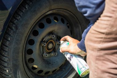 Otomotiv tamircisi tekerlek vidalarını kontrol edip yağlıyor. Romanya 'nın Bükreş kentindeki garajda araç bakımı, 2020