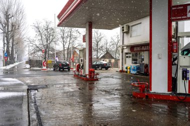 LUKOIL benzin istasyonunun dışı. Benzin pompaları ve arabalar kar yağarken yakıt ikmali yapıyorlar.
