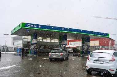 Bir OMV benzin istasyonunun dışı. Benzin pompaları ve arabalar kar yağarken yakıt ikmali yapıyorlar.
