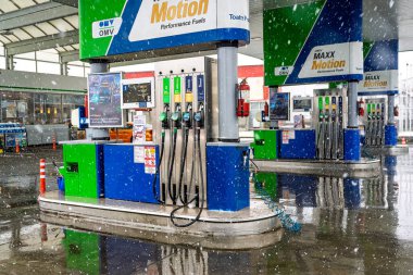 Bir OMV benzin istasyonunun dışı. Benzin pompaları ve arabalar kar yağarken yakıt ikmali yapıyorlar.