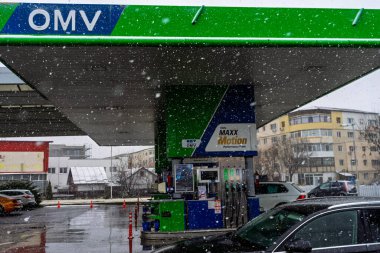 Bir OMV benzin istasyonunun dışı. Benzin pompaları ve arabalar kar yağarken yakıt ikmali yapıyorlar.