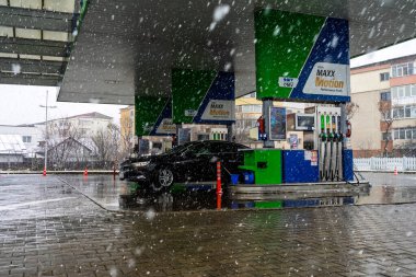 Bir OMV benzin istasyonunun dışı. Benzin pompaları ve arabalar kar yağarken yakıt ikmali yapıyorlar.