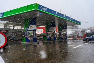 Bir OMV benzin istasyonunun dışı. Benzin pompaları ve arabalar kar yağarken yakıt ikmali yapıyorlar.