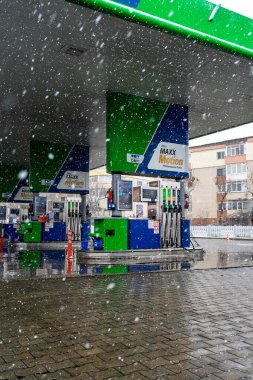 Bir OMV benzin istasyonunun dışı. Benzin pompaları ve arabalar kar yağarken yakıt ikmali yapıyorlar.