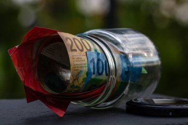 İsviçre frangı CHF banknotu cam kavanozda para biriktiriyor. Tüketim ve ekonomi. İş, bahşiş, finans, tasarruf, bankacılık ve insan kavramı