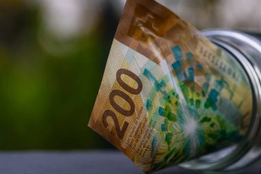 İsviçre frangı CHF banknotu cam kavanozda para biriktiriyor. Tüketim ve ekonomi. İş, bahşiş, finans, tasarruf, bankacılık ve insan kavramı