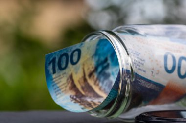 İsviçre frangı CHF banknotu cam kavanozda para biriktiriyor. Tüketim ve ekonomi. İş, bahşiş, finans, tasarruf, bankacılık ve insan kavramı