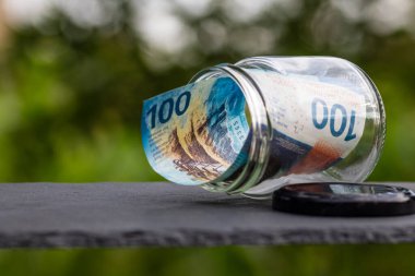 İsviçre frangı CHF banknotu cam kavanozda para biriktiriyor. Tüketim ve ekonomi. İş, bahşiş, finans, tasarruf, bankacılık ve insan kavramı
