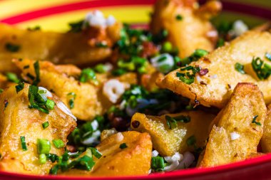 Renkli bir tabakta yeşil soğanlı, yeşil sarımsaklı ve baharatlı kızarmış patateslerin seçici odak noktasıyla kapat..