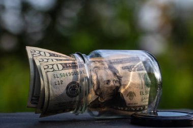 Cam kavanozda para biriktirmek için Amerikan Doları. Tüketim ve ekonomi. İş, bahşiş, finans, tasarruf, bankacılık ve insan kavramı