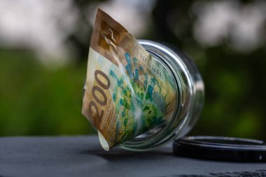 İsviçre frangı CHF banknotu cam kavanozda para biriktiriyor. Tüketim ve ekonomi. İş, bahşiş, finans, tasarruf, bankacılık ve insan kavramı