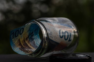 İsviçre frangı CHF banknotu cam kavanozda para biriktiriyor. Tüketim ve ekonomi. İş, bahşiş, finans, tasarruf, bankacılık ve insan kavramı