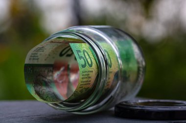 İsviçre frangı CHF banknotu cam kavanozda para biriktiriyor. Tüketim ve ekonomi. İş, bahşiş, finans, tasarruf, bankacılık ve insan kavramı
