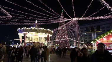 Gece Bükreş Noel pazarında süslü ağaçlar, renkli dönme dolaplar ve tatil pazarının tadını çıkaran insanlar