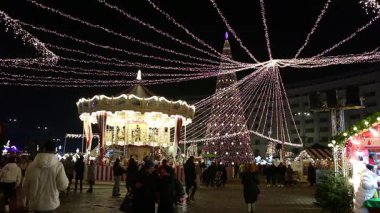 Gece Bükreş Noel pazarında süslü ağaçlar, renkli dönme dolaplar ve tatil pazarının tadını çıkaran insanlar