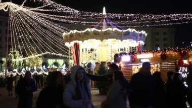 Gece Bükreş Noel pazarında süslü ağaçlar, renkli dönme dolaplar ve tatil pazarının tadını çıkaran insanlar