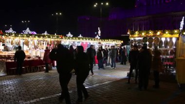 Gece Bükreş Noel pazarında süslü ağaçlar, renkli dönme dolaplar ve tatil pazarının tadını çıkaran insanlar