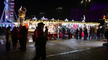 Gece Bükreş Noel pazarında süslü ağaçlar, renkli dönme dolaplar ve tatil pazarının tadını çıkaran insanlar