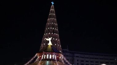 Gece Bükreş Noel pazarında süslü ağaçlar, renkli dönme dolaplar ve tatil pazarının tadını çıkaran insanlar