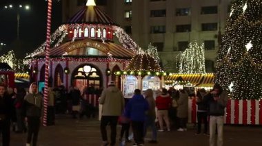 Gece Bükreş Noel pazarında süslü ağaçlar, renkli dönme dolaplar ve tatil pazarının tadını çıkaran insanlar