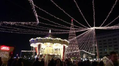 Gece Bükreş Noel pazarında süslü ağaçlar, renkli dönme dolaplar ve tatil pazarının tadını çıkaran insanlar