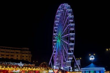Gece Bükreş Noel pazarında süslü ağaçlar, renkli dönme dolaplar ve tatil pazarının tadını çıkaran insanlar