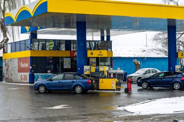 PETROM benzin istasyonunun dışı. Benzin pompaları ve arabalar kar yağarken yakıt ikmali yapıyorlar.