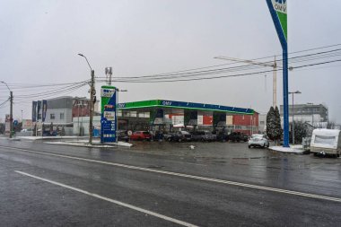 Bir OMV benzin istasyonunun dışı. Benzin pompaları ve arabalar kar yağarken yakıt ikmali yapıyorlar.