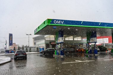Bir OMV benzin istasyonunun dışı. Benzin pompaları ve arabalar kar yağarken yakıt ikmali yapıyorlar.