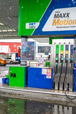 Bir OMV benzin istasyonunun dışı. Benzin pompaları ve arabalar kar yağarken yakıt ikmali yapıyorlar.