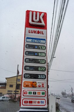 LUKOIL benzin istasyonunun dışı. Benzin pompaları ve arabalar kar yağarken yakıt ikmali yapıyorlar.