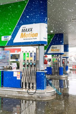 Bir OMV benzin istasyonunun dışı. Benzin pompaları ve arabalar kar yağarken yakıt ikmali yapıyorlar.